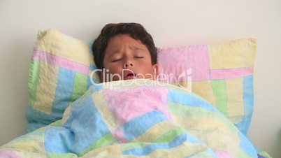 Sick child lying in bed and coughing