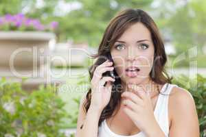 Shocked Young Adult Female Talking on Cell Phone Outdoors