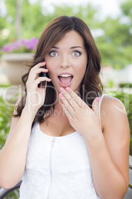 Shocked Young Adult Female Talking on Cell Phone Outdoors