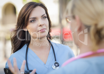 Two Young Adult Female Doctors or Nurses Talking Outside