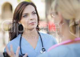 Two Young Adult Female Doctors or Nurses Talking Outside