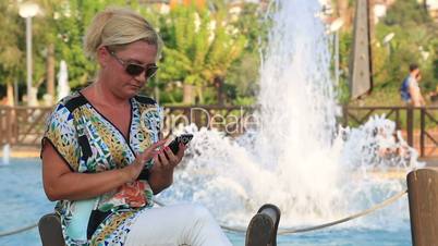 Woman sitting on the park bench and sending text  Message