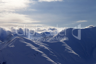 Snowy mountains in mist at sun evening