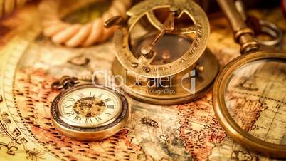 Vintage magnifying glass, compass, telescope and a pocket watch lying on ancient world map in 1565.