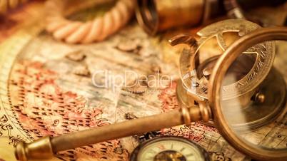 Vintage magnifying glass, compass, telescope and a pocket watch lying on ancient world map in 1565.