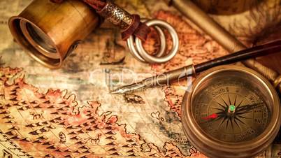 Vintage magnifying glass, compass, telescope and a pocket watch lying on ancient world map in 1565.