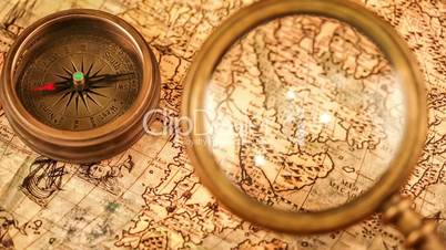 Vintage still life. Vintage magnifying glass lies and compass on ancient world map in 1565.