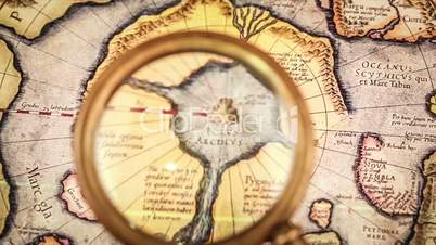 Vintage magnifying glass lies on the ancient map of the North Pole (also Hyperborea). Arctic continent on the Gerardus Mercator map of 1595.