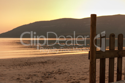 little fence on the beach with the sea at sunset