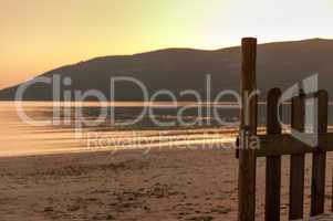 little fence on the beach with the sea at sunset