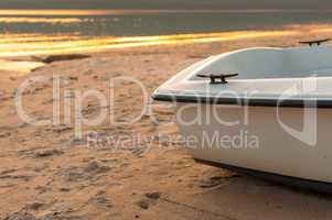 small boat on the beach with the sea at sunset