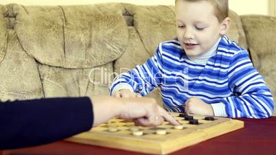 little boy plays checkers with his grandmother