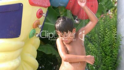 Happy child taking a cold shower in a waterpark