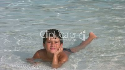 Child in swimming pool smiling to a camera