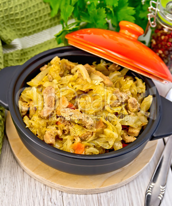 Cabbage stew with meat in black pot on board