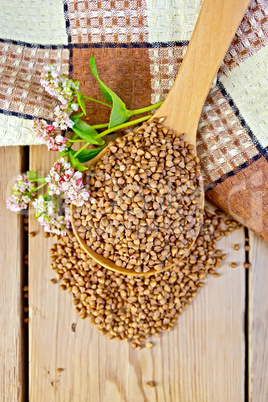 Buckwheat in spoon and napkin with flower on board