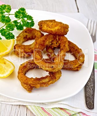 Calamari fried with lemon and fork on plate and napkin