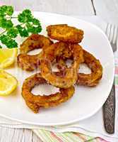 Calamari fried with lemon and fork on plate and napkin
