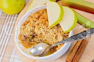 Crumble with pears and rhubarb in bowl on linen tablecloth