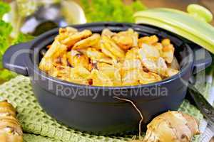 Jerusalem artichokes roasted in pan with lid on board