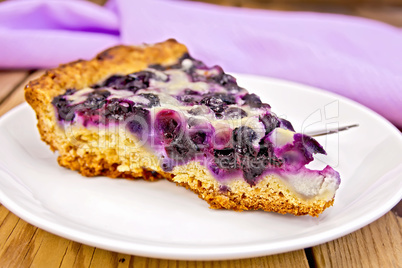Pie with blueberries and spoon in plate on board
