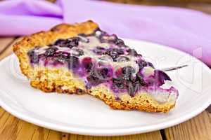 Pie with blueberries and spoon in plate on board