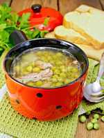 Soup from green peas with meat in red bowl
