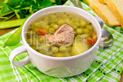 Soup from green peas with meat on green napkin