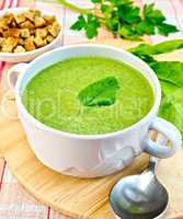 Soup puree with spinach leaves and spoon on fabric