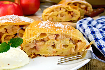 Strudel with apples in bowl with ice cream on board