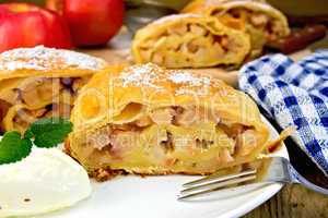 Strudel with apples in bowl with ice cream on board