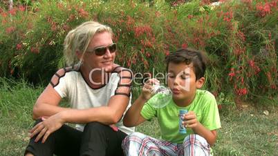 Mother and son blowing bubbles in the park
