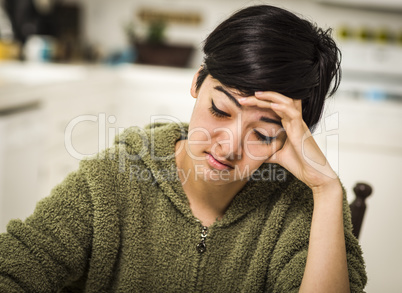 Depressed Mixed Race Young Woman Sitting Alone In Kitchen