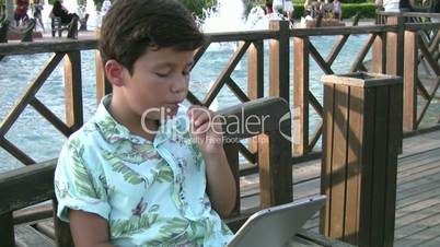 child using digital tablet and eating candy