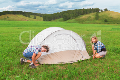 Teenage boy and girl arranges tourist tent