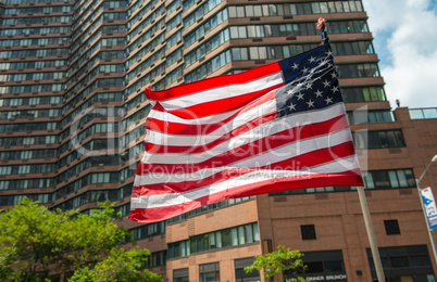 American flag waving with city building on background