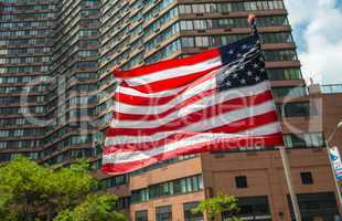 American flag waving with city building on background