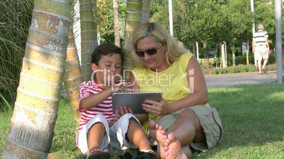 Mother and son using digital tablet in the park