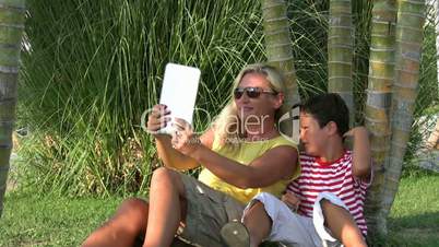 Mother and son sitting in the park and taking selfie