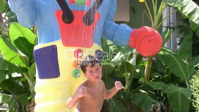 child taking a cold shower in a waterpark and dancing