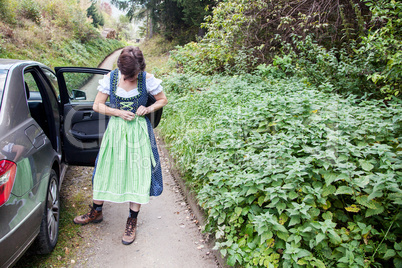 Woman standing next to the car and directed her dirndl dress