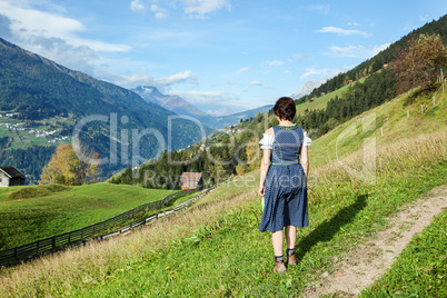 Woman in dirndl looks into the valley