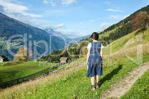 Woman in dirndl looks into the valley