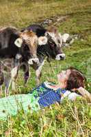 Woman in dirndl is before their cows in the grass