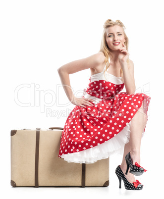 Frau sitzt auf Koffer und wartet