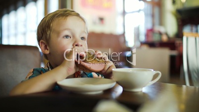 Little boy eating sandwich in a cafe