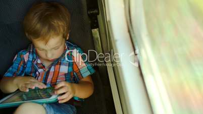 Boy in train using tablet computer