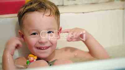 Happy little boy in bath with toys