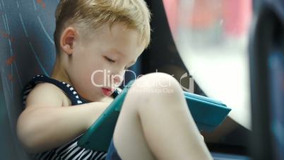 Little boy in car using tablet computer