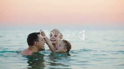 Young parents with son bathing in sea